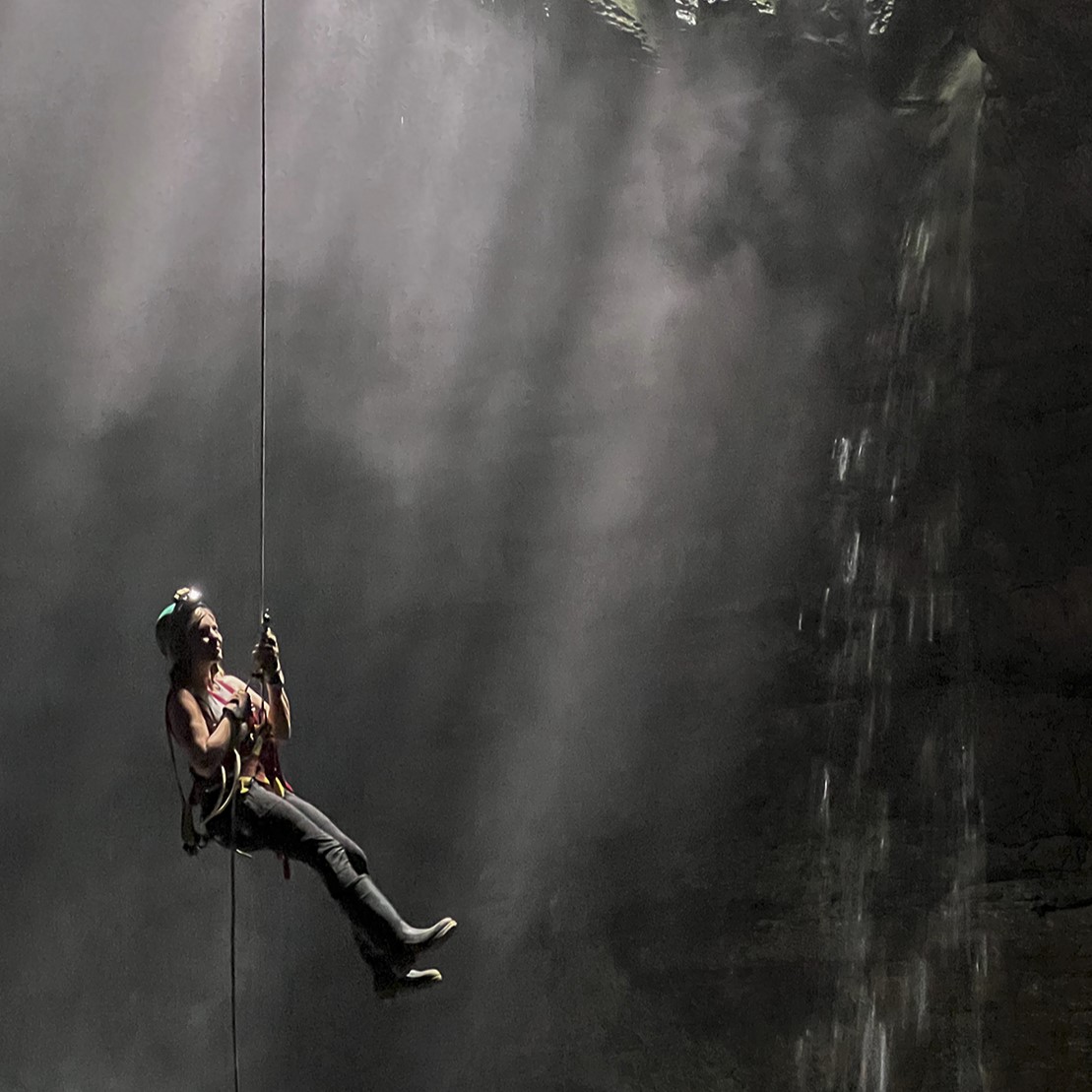 photo of woman climbing out of a pit cave